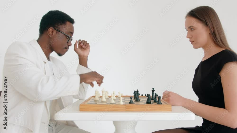 Caucasian girl takes off the ring and puts it on the chessboard during game with her african american guy. Relationship breakup concept