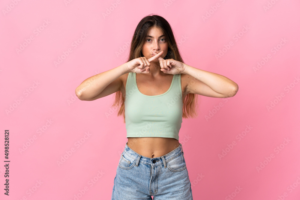 Young caucasian woman isolated on pink background showing a sign of silence gesture