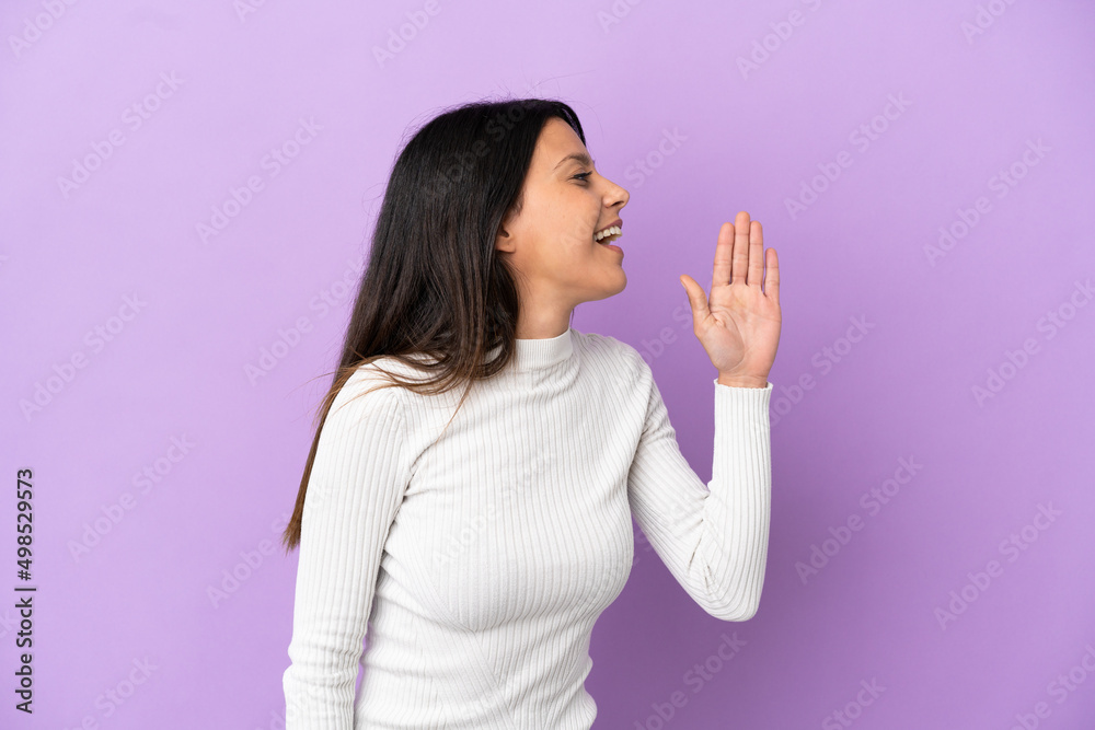 Young caucasian woman isolated on purple background shouting with mouth wide open to the side Young caucasian woman isolated on purple background shouting with mouth wide open to the side