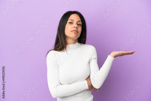 Young caucasian woman isolated on purple background having doubts © luismolinero