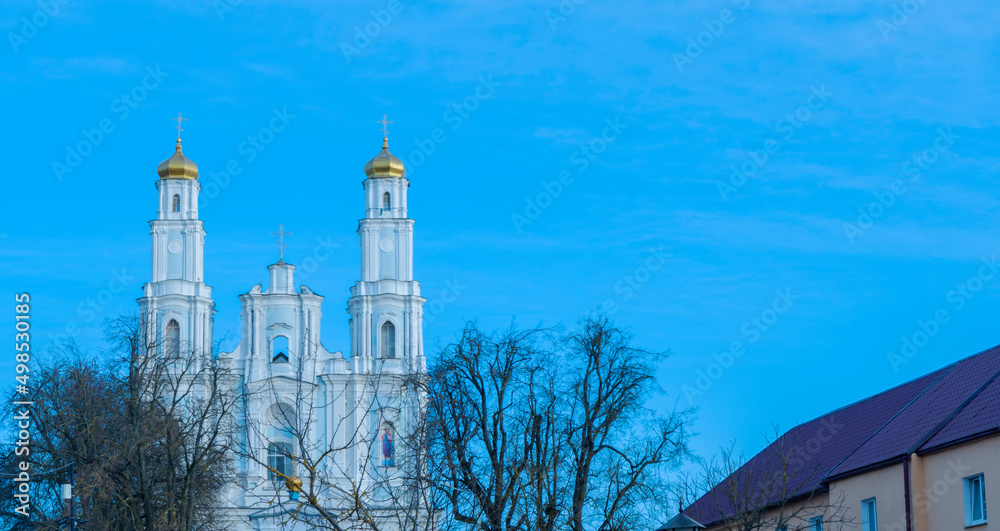 Dome of Russian orthodox church on blue sky background. In foreground silhouette of bare branches. Worship and Easter.