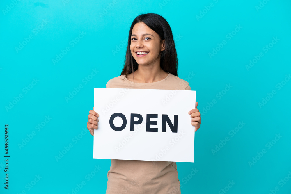 Young woman over isolated background holding a placard with text OPEN with happy expression Young woman over isolated background holding a placard with text OPEN with happy expression