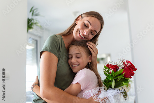 I love my you mom! Attractive young woman with little cute girl are spending time together at home, thanking for handmade card with love symbol and flowers. Happy family concept. Mother's day. © Graphicroyalty