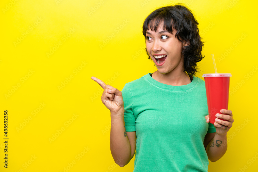 Young Argentinian woman holding a soda isolated on yellow background intending to realizes the solution while lifting a finger up Young Argentinian woman holding a soda isolated on yellow background intending to realizes the solution while lifting a finger up