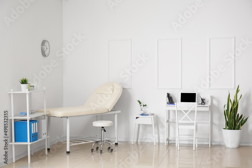 Doctor's workplace with laptop and couch in medical office