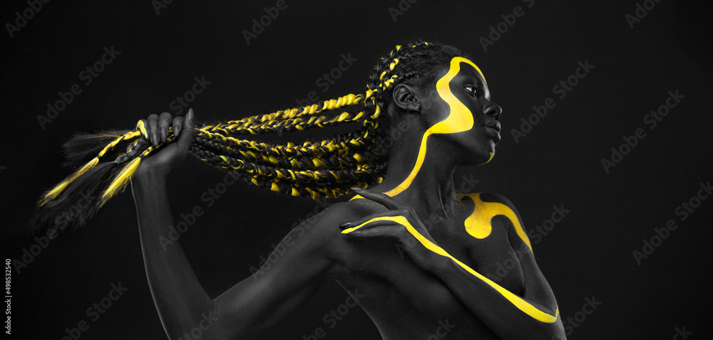 Yellow and black body paint. Woman with face art. Young girl with  bodypaint. An amazing model with makeup. Stock Photo