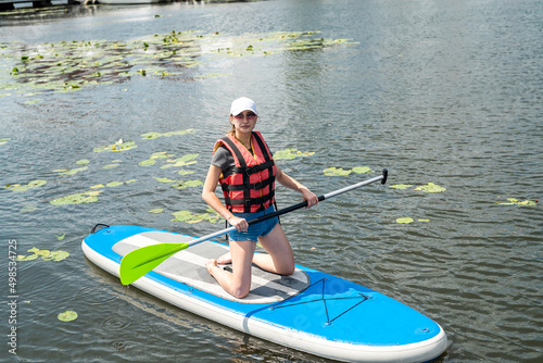 Young Woman wear Life vest rest on Paddle Board after the first training session