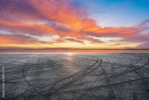 Canvastavla Empty asphalt road and lake with sky sunset clouds background