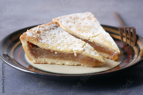 slice of apple pie cake on a plate on black background 