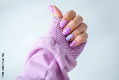 Women's hands with a fashionable very peri manicure . Hands with spring - summer purple square-shaped nails.