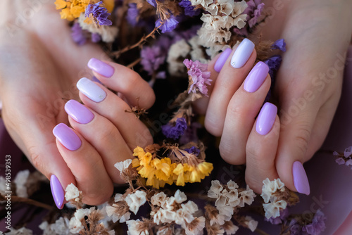 Vászonkép Women's hands with a fashionable very peri manicure against the background of dried flowers