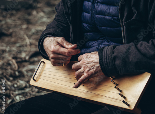 Unidentified elderly man plays the harp. Hands closeup photo