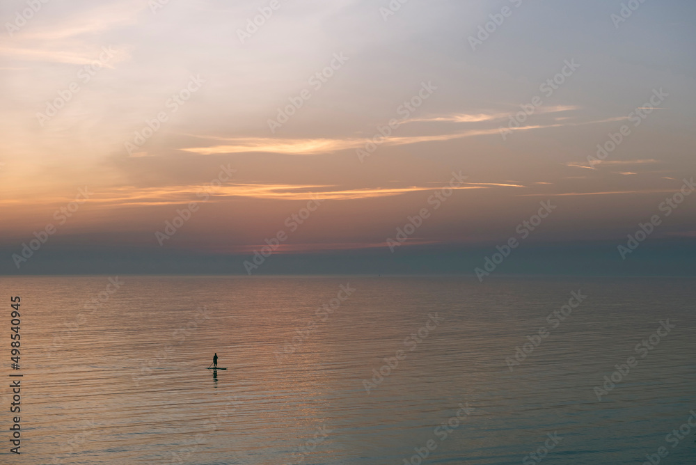 Man paddle boarding on sea during sunset