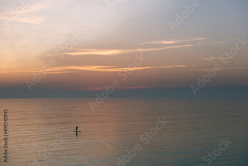 Man paddle boarding on sea during sunset