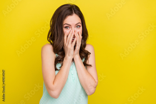 Photo of cute good mood giggling lady cover her face laughing hear funny joke isolated on yellow color background