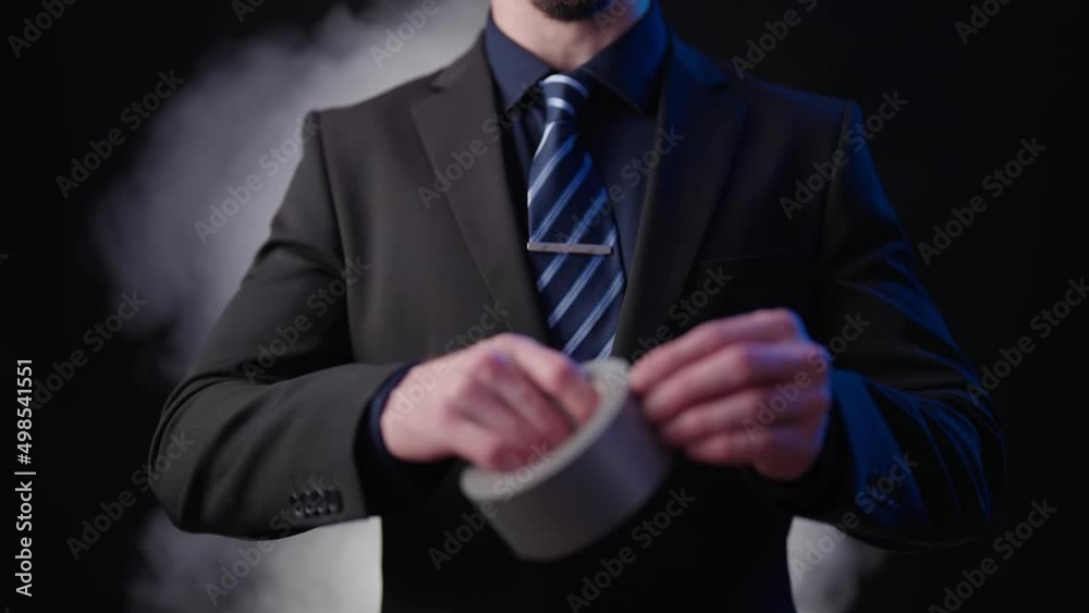 Headless businessman on black background roll out silver tape blasting smoke 4K Headless businessman on black background roll out silver tape blasting smoke 4K