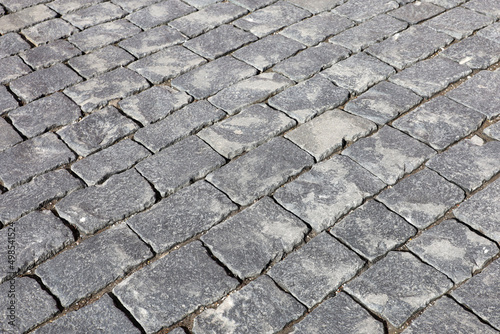 Gray stone pavement texture, cobbled street. Old paved road with tiles from cobblestones