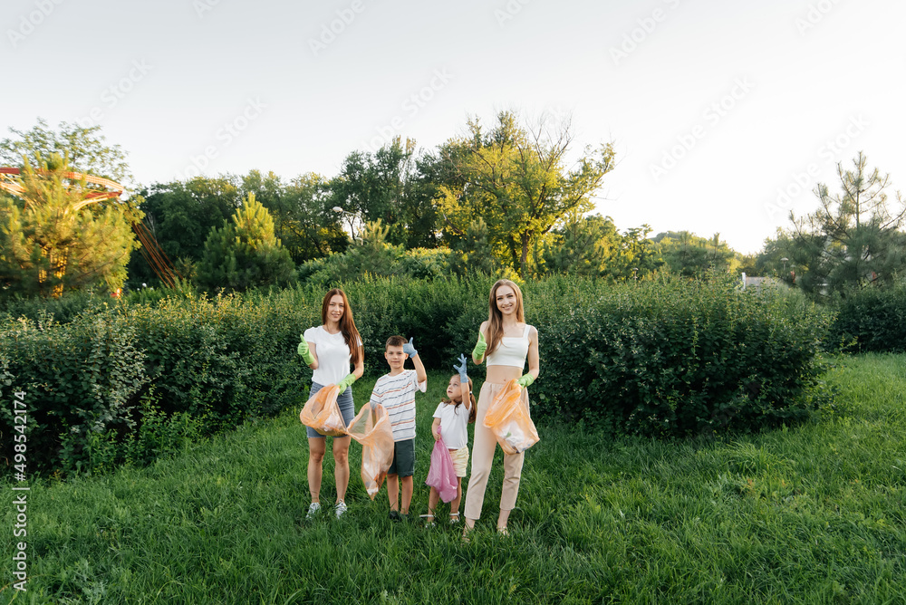 Obraz premium A group of adults and children together at sunset is engaged in garbage collection in the park. Environmental care, waste recycling. Sorting garbage.