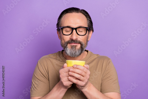 Portrait of handsome dreaming peaceful man feel nice smell of yummy coffee with closed eyes isolated on violet color background