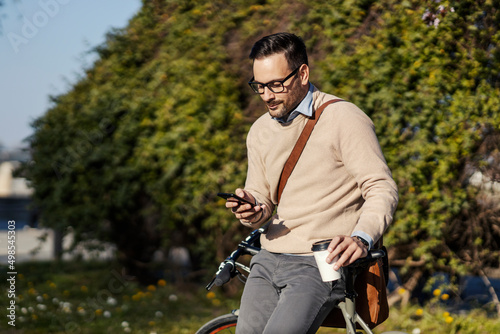 A man in public park leaning on bicycle and taking a break.