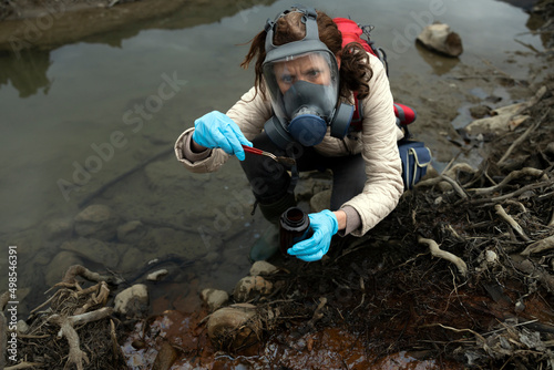 Biologist With Gas Mask and Protective Latex Blue Gloves Taking Samples of Soil With Pincette photo