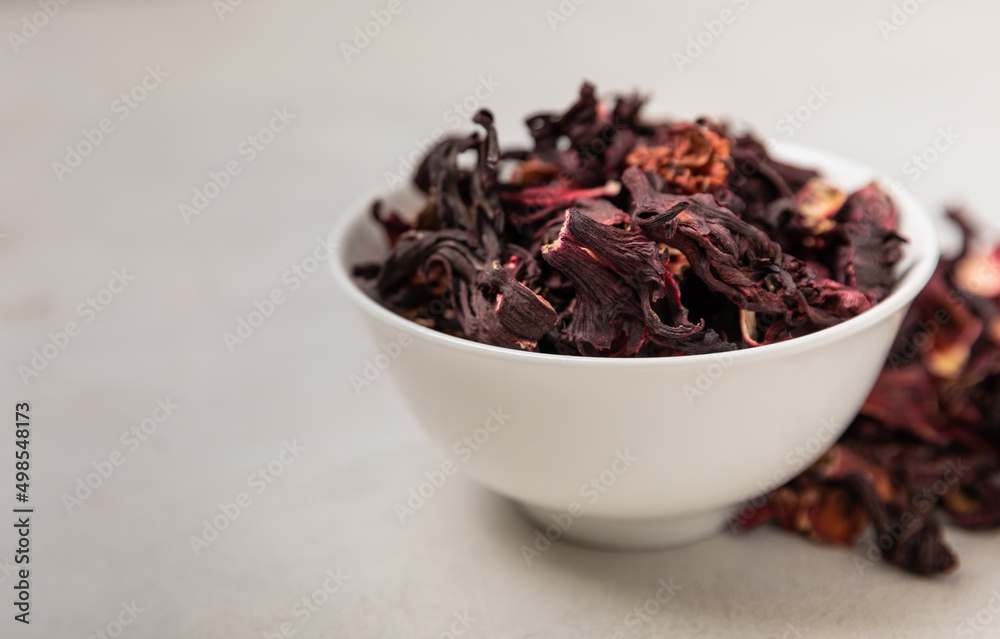 Hibiscus tea. Hibiscus tea in a white ceramic bowl on a gray cement background.Vitamin tea for colds and flu.Copy space. Hibiscus tea. Hibiscus tea in a white ceramic bowl on a gray cement background.Vitamin tea for colds and flu.Copy space.