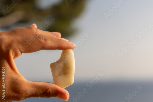 main qui tient une pierre qui a la forme de l'île méditerranéenne de la corse