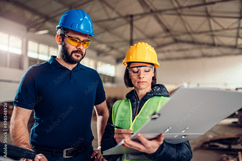 Factory supervisor checking production schedule at CNC machine Factory supervisor checking production schedule at CNC machine