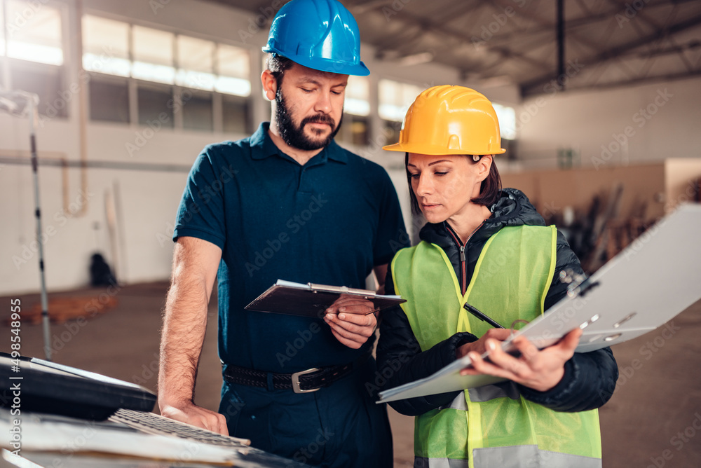 Fototapeta premium CNC Machine Operator and industrial engineer analyzing technical drawing