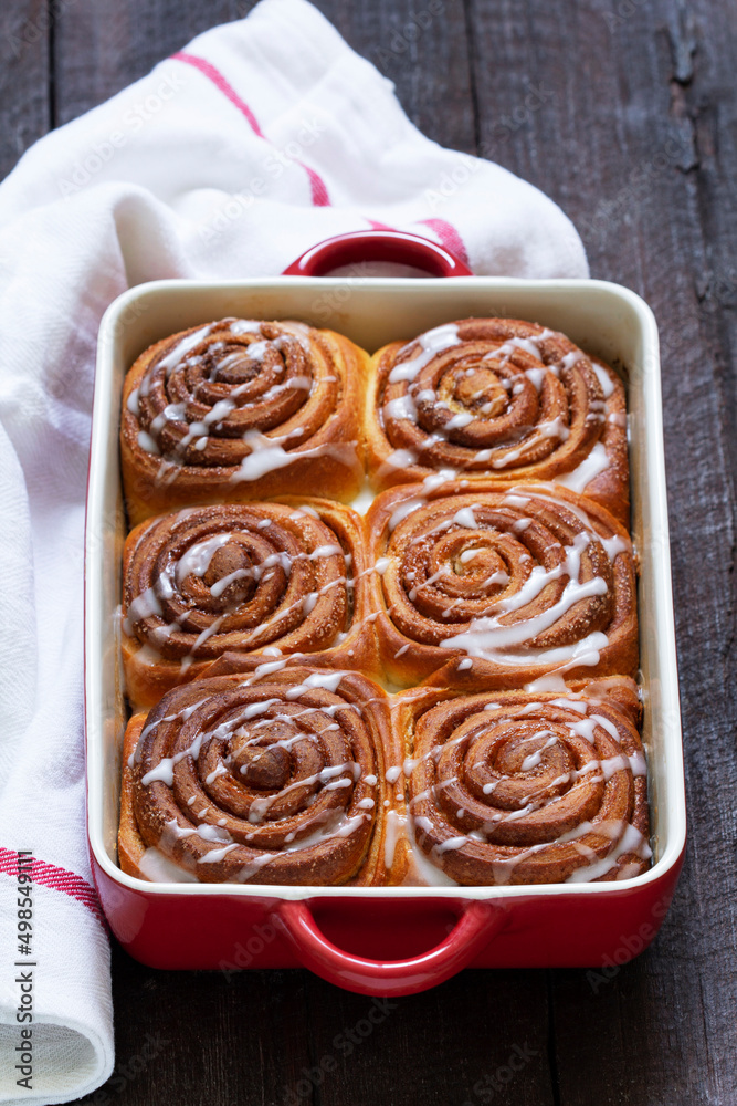 Traditional cinnamon buns with icing on a wooden table. Rustic style.