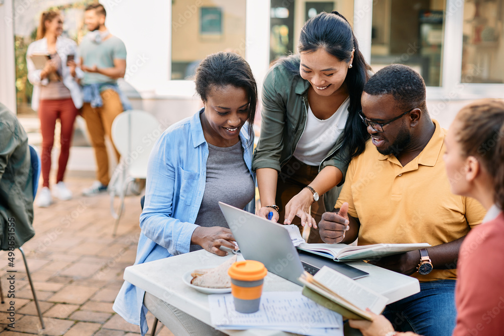 Multiracial group of happy college students learning together at cafeteria. Multiracial group of happy college students learning together at cafeteria.