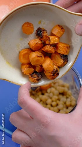 Vertical flat lay video: cooking humus, chef adds fried carrot to the nutt in the blender bowl, making vegetarian meal photo