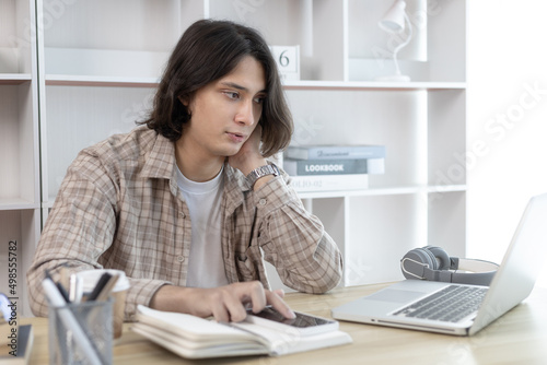 Young student does his homework and is broadcast live on his laptop during the semester break, Stay home, New normal, Distance learning, Social distancing, Learn online, Long distance communication.