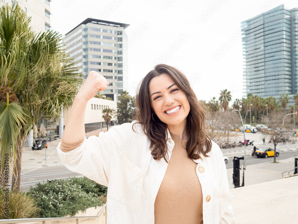 Young smiling business woman showing off biceps. Empowered woman