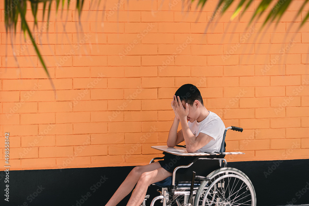 Obraz premium Young man with disability have some things to think about that can lead to depression,Teenager boy sitting with tray for activities on wheelchair,Sad emotional or depression and mental health concept.