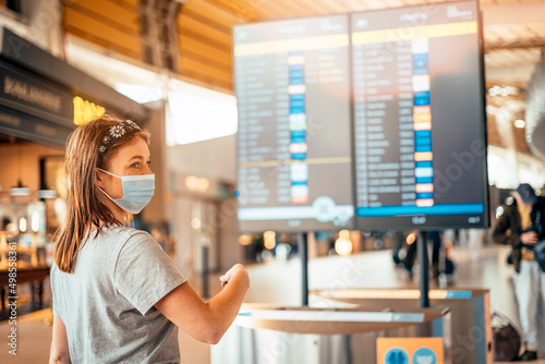 A young woman in mask by information board at the airport