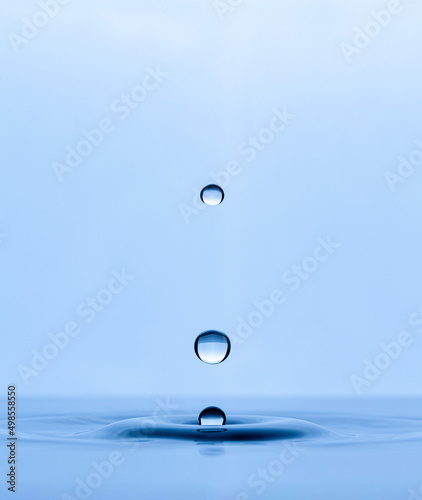 Splash and a ball of water on a blue background. Reflection on the surface of the water.