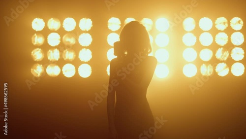 Silhouette woman singer moving seductively in studio. Hot girl singing solo. photo