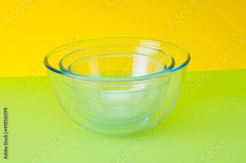 Empty glass food bowls on  green and yellow background