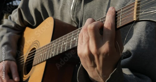 The guitarist plays the acoustic guitar close-up. Open air