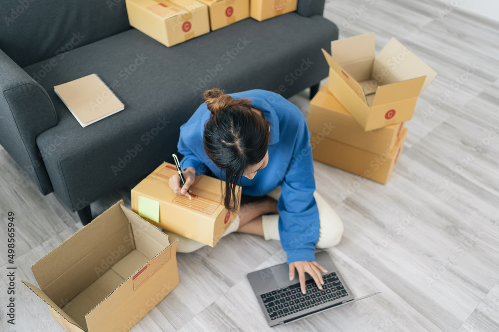 Fototapeta premium Starting small businesses SME owners female entrepreneurs Write the address on receipt box and check online orders to prepare to pack the boxes, sell to customers, sme business ideas online.