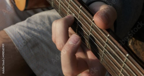 The guitarist plays the acoustic guitar close-up. Open air