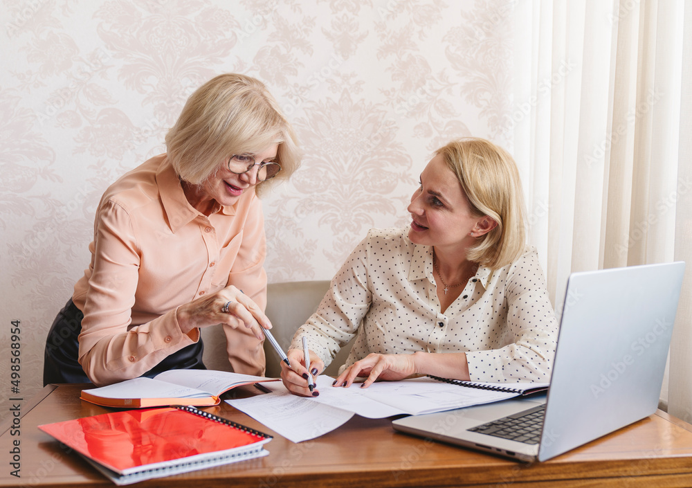 Mature business women discuss documents in the home office. Mature business women discuss documents in the home office.