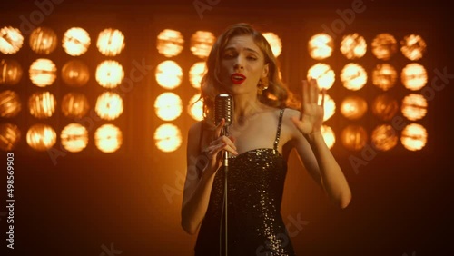 Glamour woman singer dancing on stage close up. Girl vocalist singing in club.