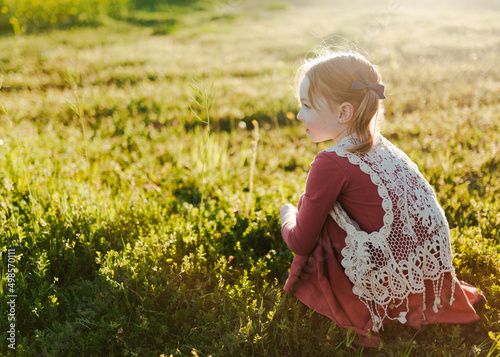 young girl sitting in a green field photo