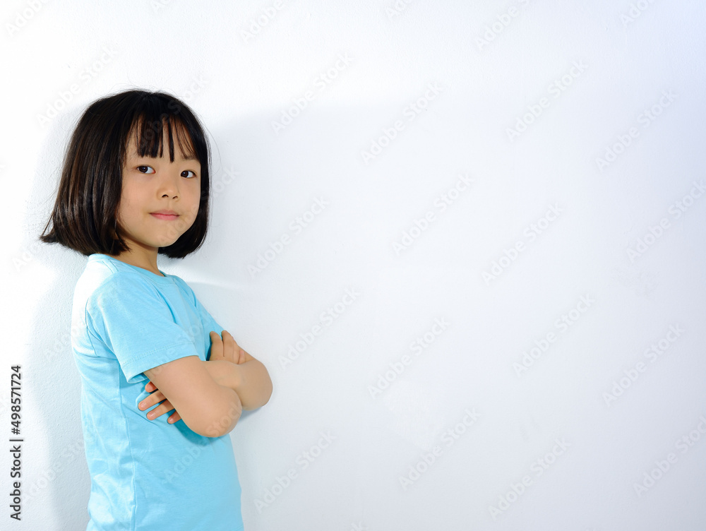 Asian girl folded in blue shirt against white plaster background. Asian girl folded in blue shirt against white plaster background.