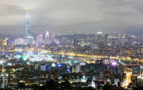 Aerial view of Taipei City with Taipei 101 tower standing tall into clouds, and Keelung River and skyscrapers in downtown area in evening twilight ~ Scenery of foggy Taipei City with polluted hazy air © AaronPlayStation