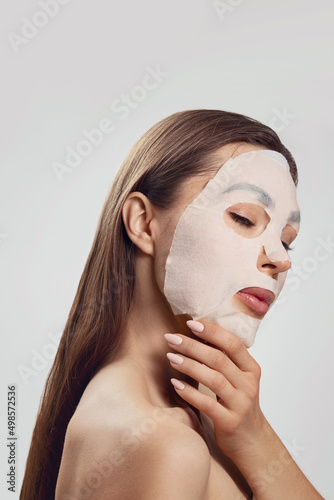 Beautiful woman with a cloth moisturizing mask for the face. Facial and Spa treatment . Cosmetic mask.