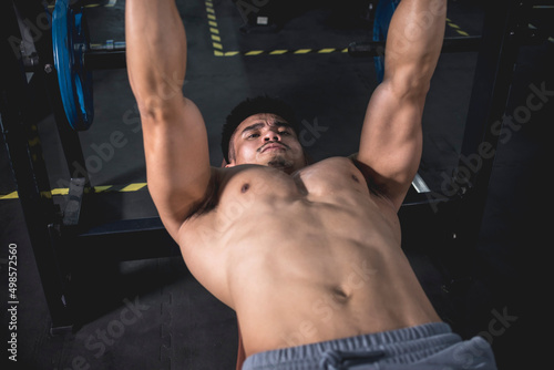 A fit asian man squeezing his pecs to get the extra pump while doing dumbbell bench presses. Working out chest muscles. photo