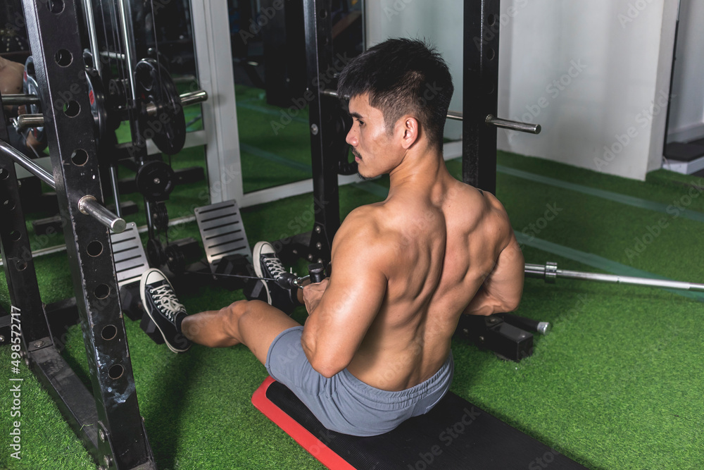 A shirtless asian man performing seated Vbar cable rows at the gym